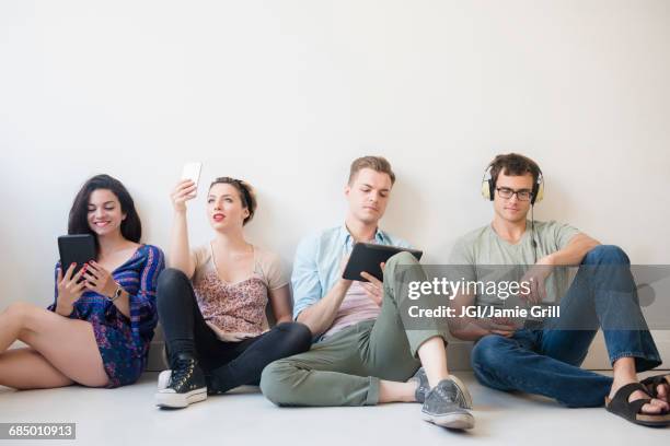 caucasian friends sitting on floor using technology - sitting and using smartphone studio stockfoto's en -beelden