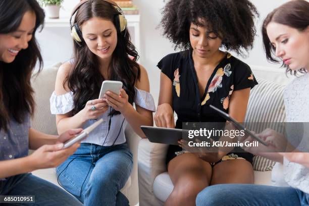 women using technology in livingroom - multiple devices stockfoto's en -beelden