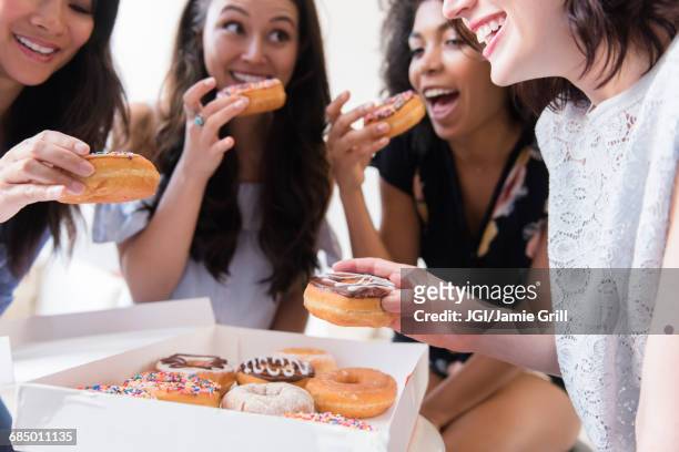 smiling women eating donuts - eating donuts foto e immagini stock