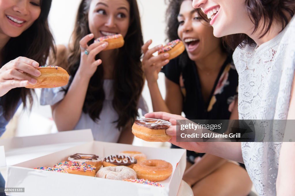 Smiling women eating donuts