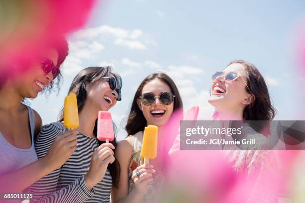 laughing women eating flavored ice outdoors - happy eating stock pictures, royalty-free photos & images