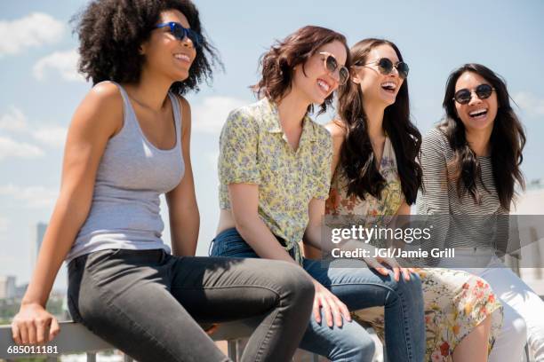 laughing women sitting on railing outdoors - quartetto foto e immagini stock