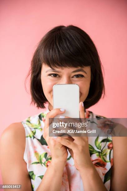 hispanic woman hiding face behind cell phone - awkward selfie stock pictures, royalty-free photos & images