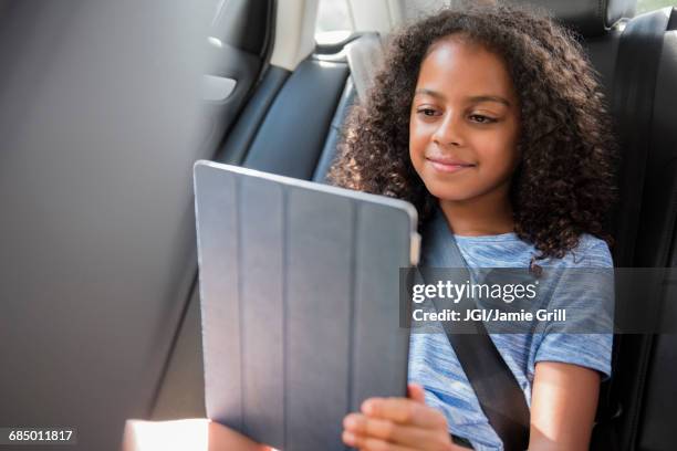 smiling hispanic girl using digital tablet in car - child car tablet ストックフォトと画像