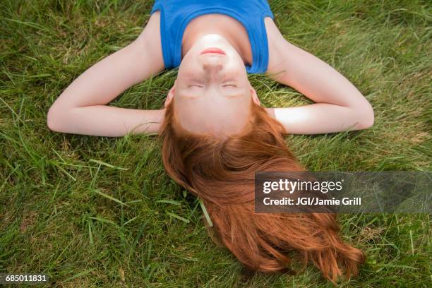 caucasian girl laying in grass with hands behind head - pale complexion stock-fotos und bilder