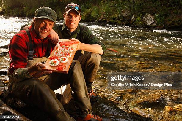 father and son with salmon sushi on the shore - cohozalm stockfoto's en -beelden