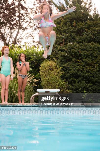 girl holding nose jumping off diving board into swimming pool - cannon ball pool stock pictures, royalty-free photos & images