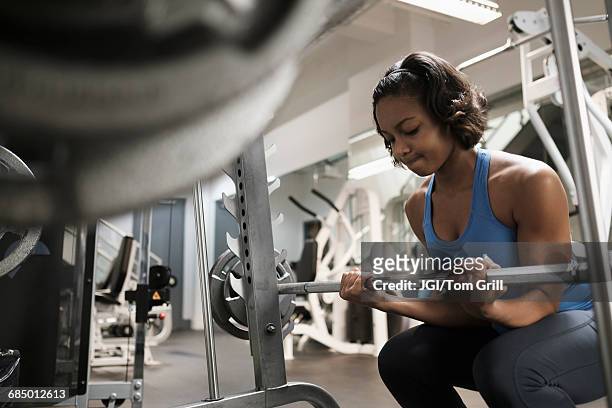 mixed race woman lifting barbell at gymnasium - musculation des biceps photos et images de collection