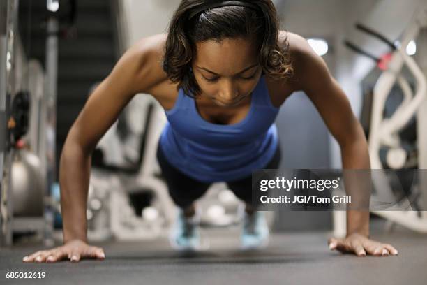 mixed race woman doing push-up on floor at gymnasium - core strength stock pictures, royalty-free photos & images