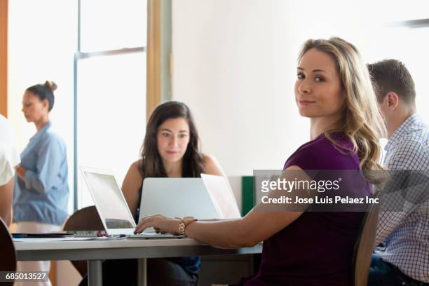portrait of businesswoman using laptop in office - business woman looking over shoulder stock pictures, royalty-free photos & images