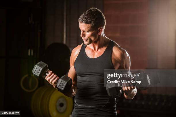 caucasian man lifting dumbbells in gymnasium - ellbogenbeuge stock-fotos und bilder