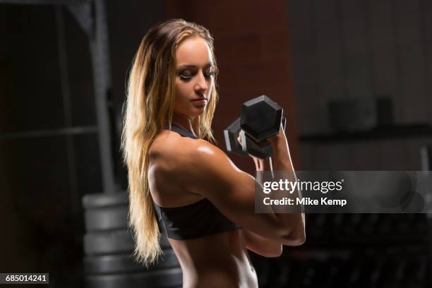 caucasian woman lifting dumbbells in gymnasium - musculation des biceps photos et images de collection