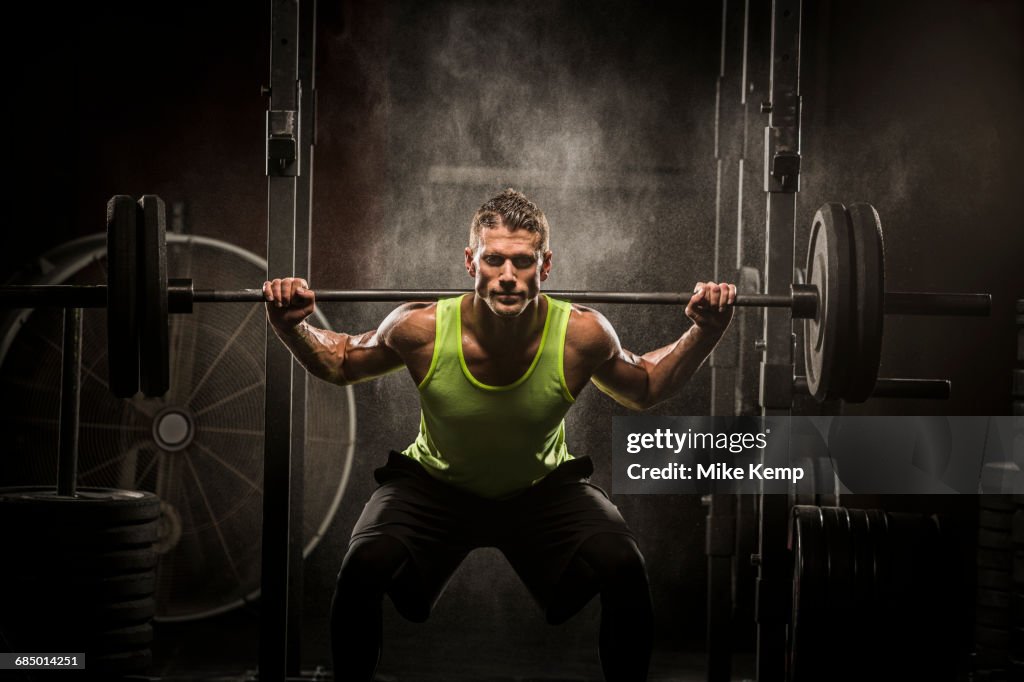 Caucasian man lifting barbell in gymnasium