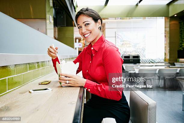 mixed race businesswoman eating food with chopsticks in food court - food court ストックフォトと画像