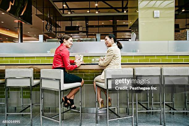 smiling businesswomen talking in food court - food court stock pictures, royalty-free photos & images