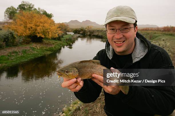 fisherman with brown trout - brown trout stock pictures, royalty-free photos & images