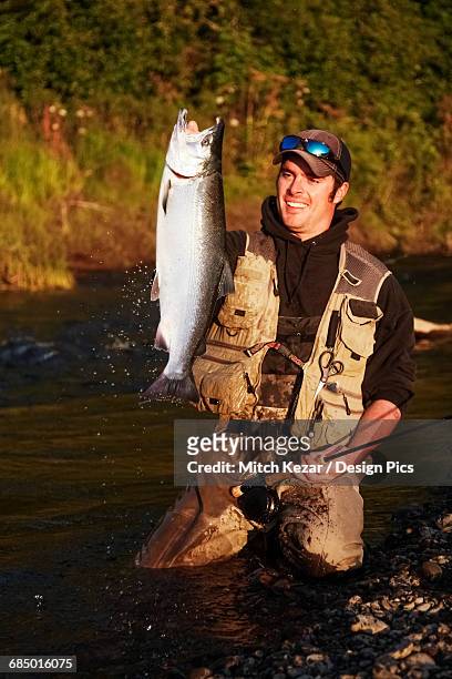 salmon fisherman holds up salmon - cohozalm stockfoto's en -beelden