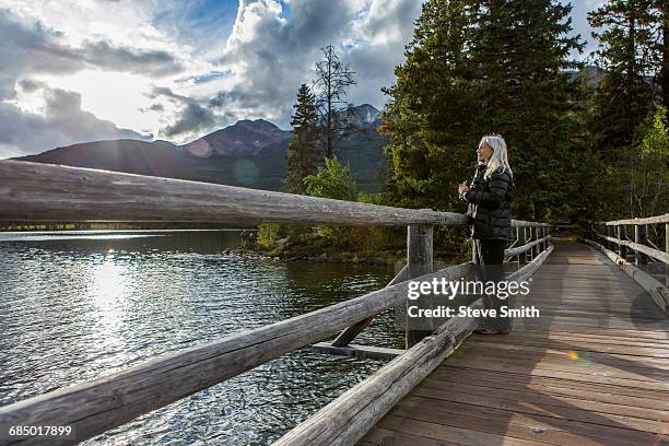 caucasian woman holding binoculars at mountain lake - bridge side view stock pictures, royalty-free photos & images
