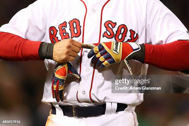 Dustin Pedroia of the Boston Red Sox takes off hid Franklin batting gloves during a game against the Chicago Cubs at Fenway Park on April 30, 2017 in...
