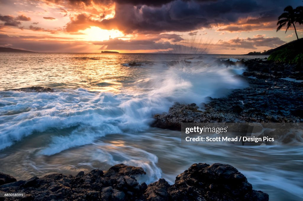 Water and foam splashing on the lava rock along the coastline of a Hawaiian island