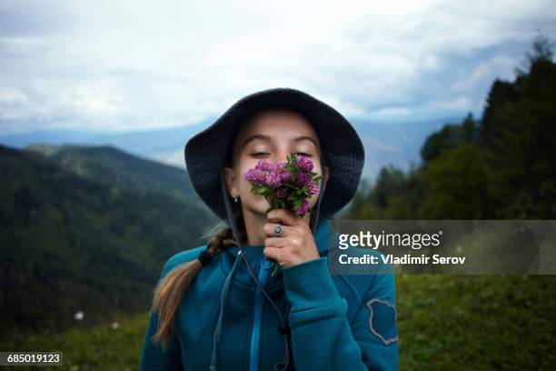 Caucasian girl smelling flowers on mountain range