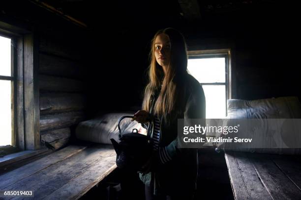 Caucasian girl holding kettle in log home