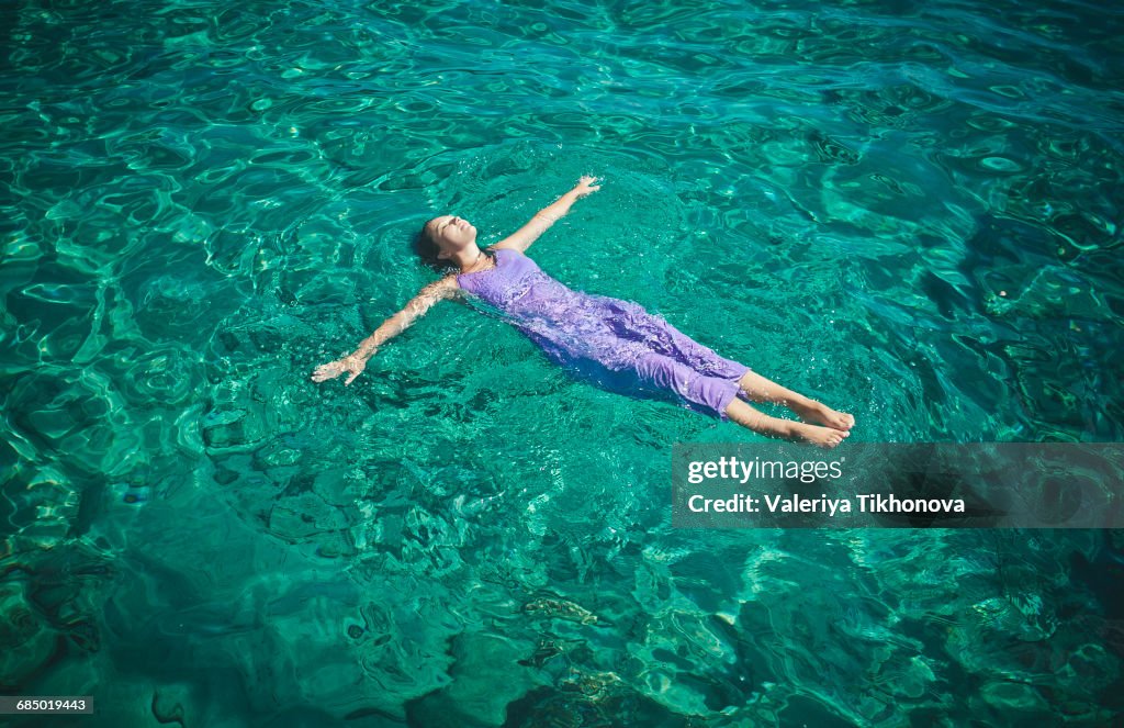 Caucasian woman wearing dress floating in water