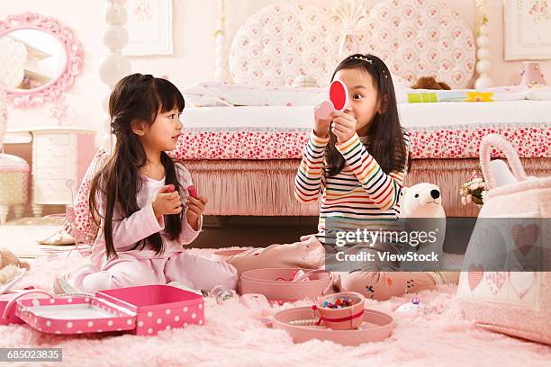 two cute little girls play in the bedroom - fersensitz stock-fotos und bilder