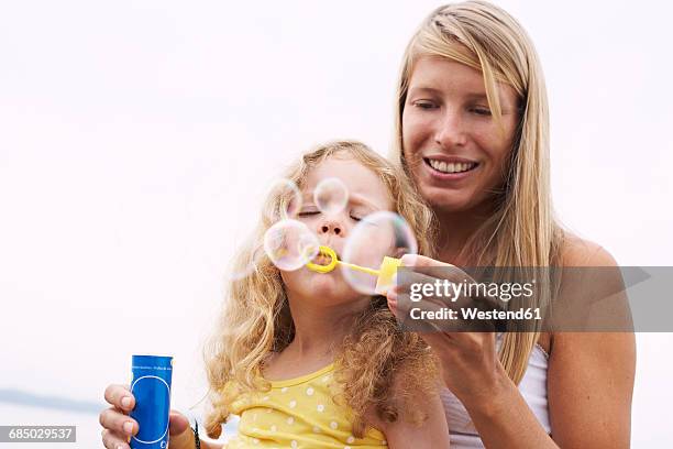 mother and daughter blowing soap bubbles - hovering mom stock pictures, royalty-free photos & images