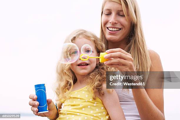 mother and daughter blowing soap bubbles - hovering mom stock pictures, royalty-free photos & images