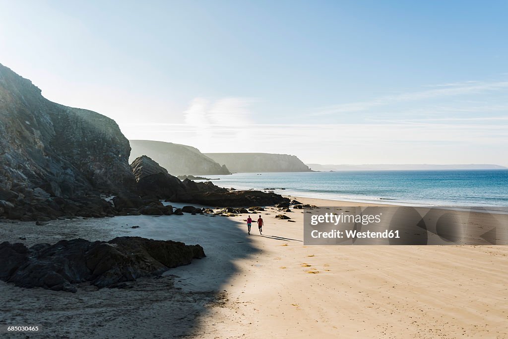 France, Crozon peninsula, young couple running on the beach