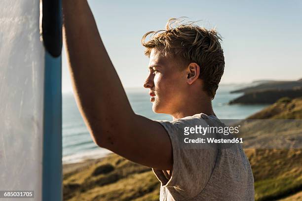 teenage boy with surfboard looking to the sea - water side view stock pictures, royalty-free photos & images