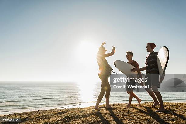 Three friends with surfboards camping at seaside