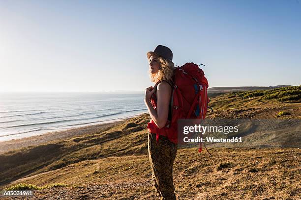 teenage girl with backpack at seaside looking at distance in the evening twilight - rucksacktourist stock-fotos und bilder