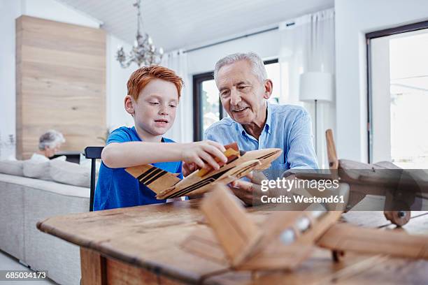 grandfather and grandson building up model airplanes - two elderly men dressed in 70's outfits stock pictures, royalty-free photos & images