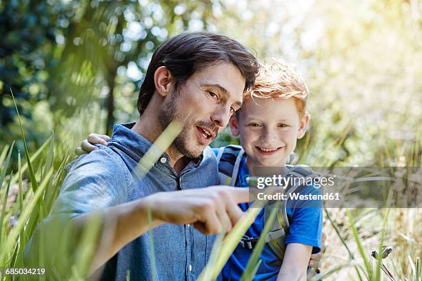 father showing son a grasshopper - grashüpfer stock-fotos und bilder