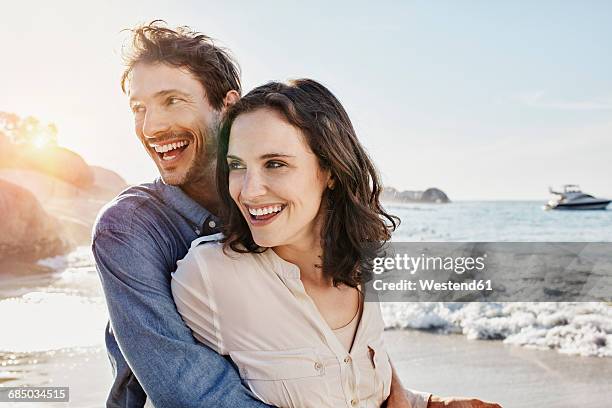 happy couple hugging on the beach - back lit man stock pictures, royalty-free photos & images