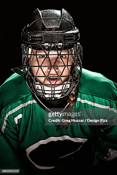 ringette player wearing green jersey with helmet and cage - hockey player black background stock pictures, royalty-free photos & images
