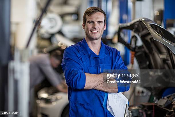 confident car mechanic in repair garage - mechanic portrait stock-fotos und bilder