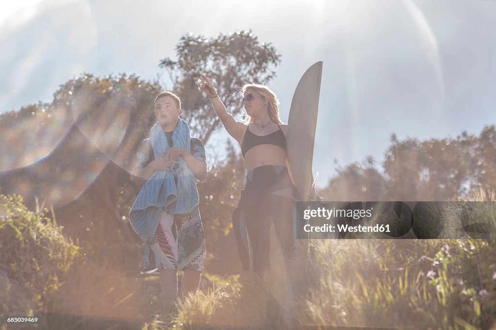 Teenage boy with down syndrome and woman with surfboard at the coast