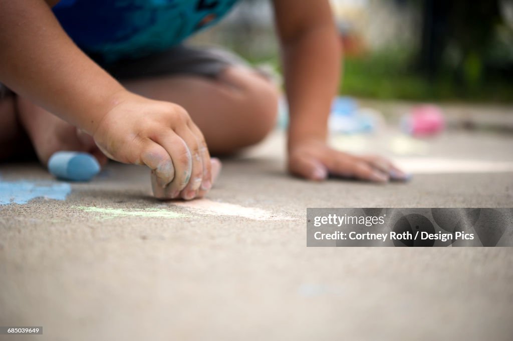 Child playing with sidewalk chalk