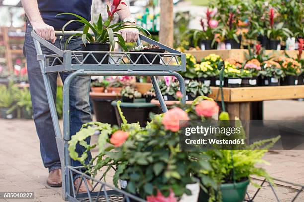 man pushing a trolley full of plants in garden centre - tuincentrum stockfoto's en -beelden