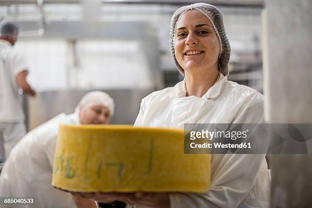 cheese factory worker holding labeled cheese wheel - dairy product stock-fotos und bilder