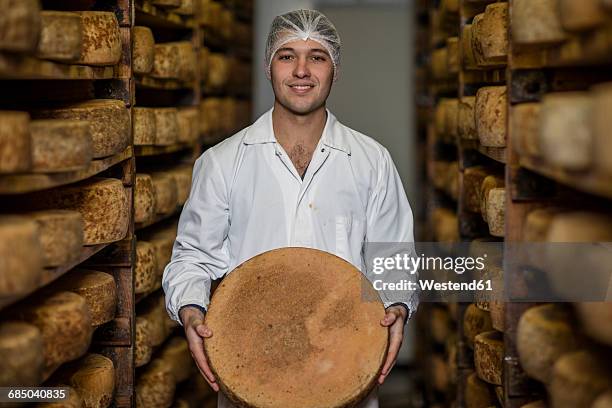 cheese factory worker proudly holding loaf of cheese - wiel kaas stockfoto's en -beelden