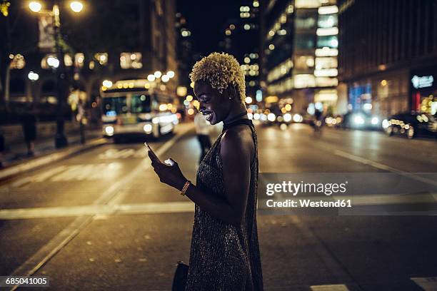 usa, new york city, smiling young woman on times square at night looking at cell phone - beautiful woman on the street of new york city stock-fotos und bilder