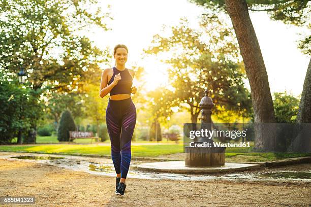 young woman jogging in park at sunset - joggerin park stock-fotos und bilder