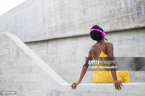 back view of woman listening music with pink headphones - leaning stock pictures, royalty-free photos & images