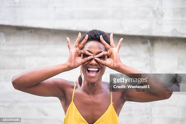 laughing woman forming spectacles with fingers - smala axelband bildbanksfoton och bilder