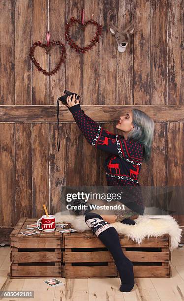 young woman wearing patterned knit pullover and overknees taking selfie with polaroid camera - tattoo designs hearts - fotografias e filmes do acervo