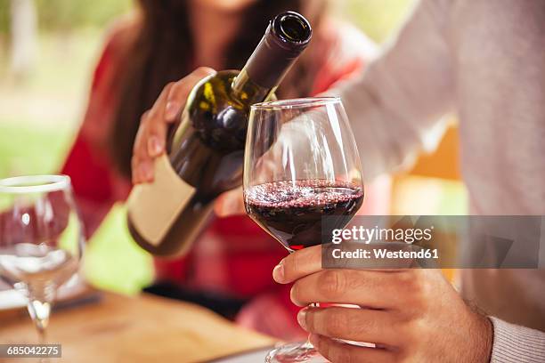 man pouring red wine into glass - red wine photos et images de collection